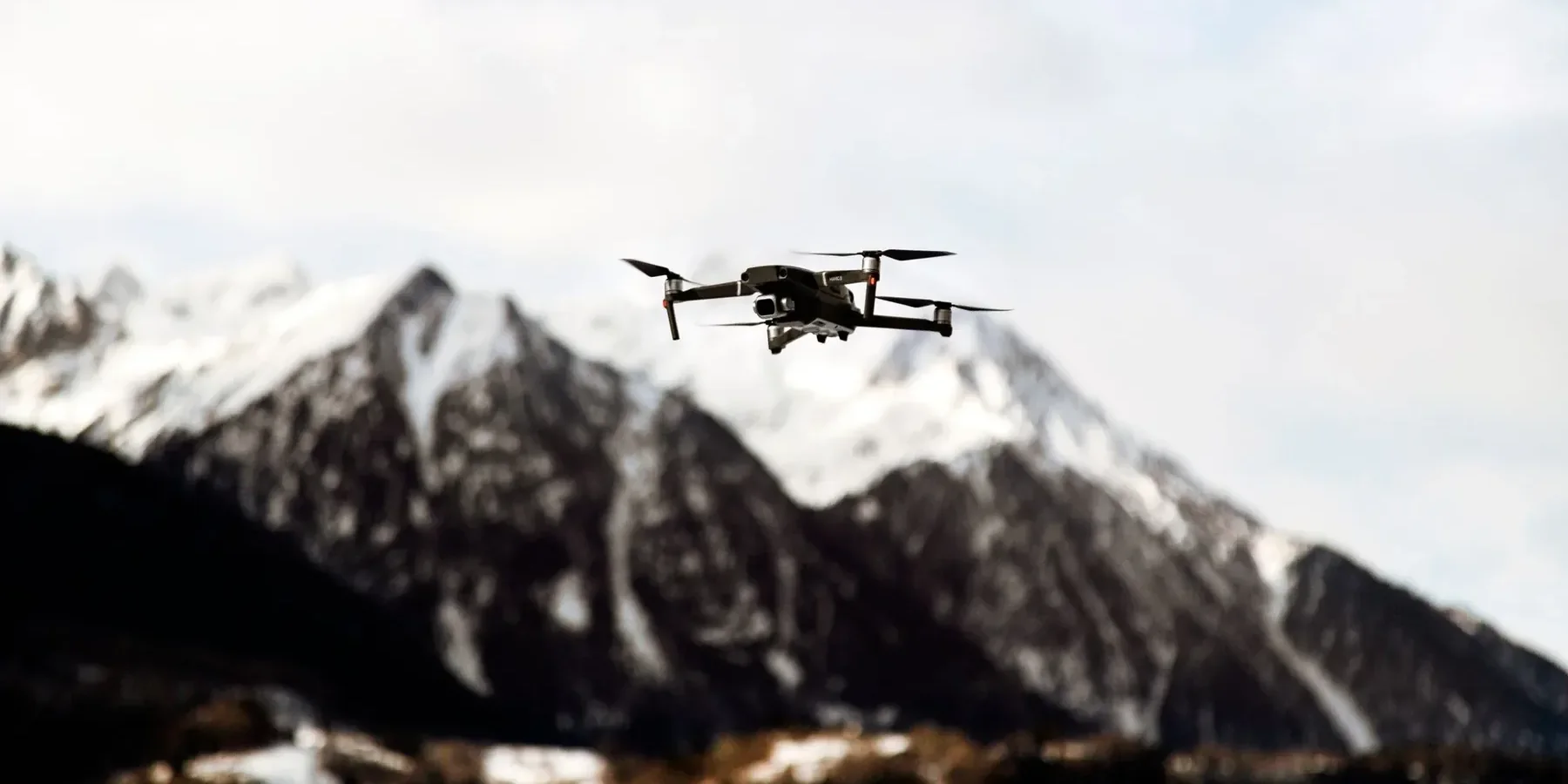 A camera drone flying over a mountainous landscape, illustrating why Chinese registration and flight rules matter