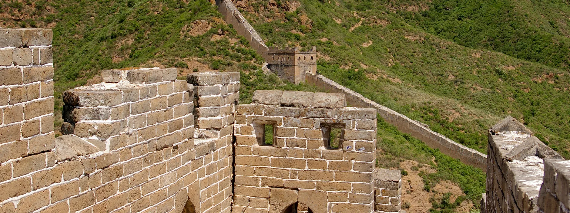 Jinshanling Great Wall stretching across a forested ridge, tower after tower