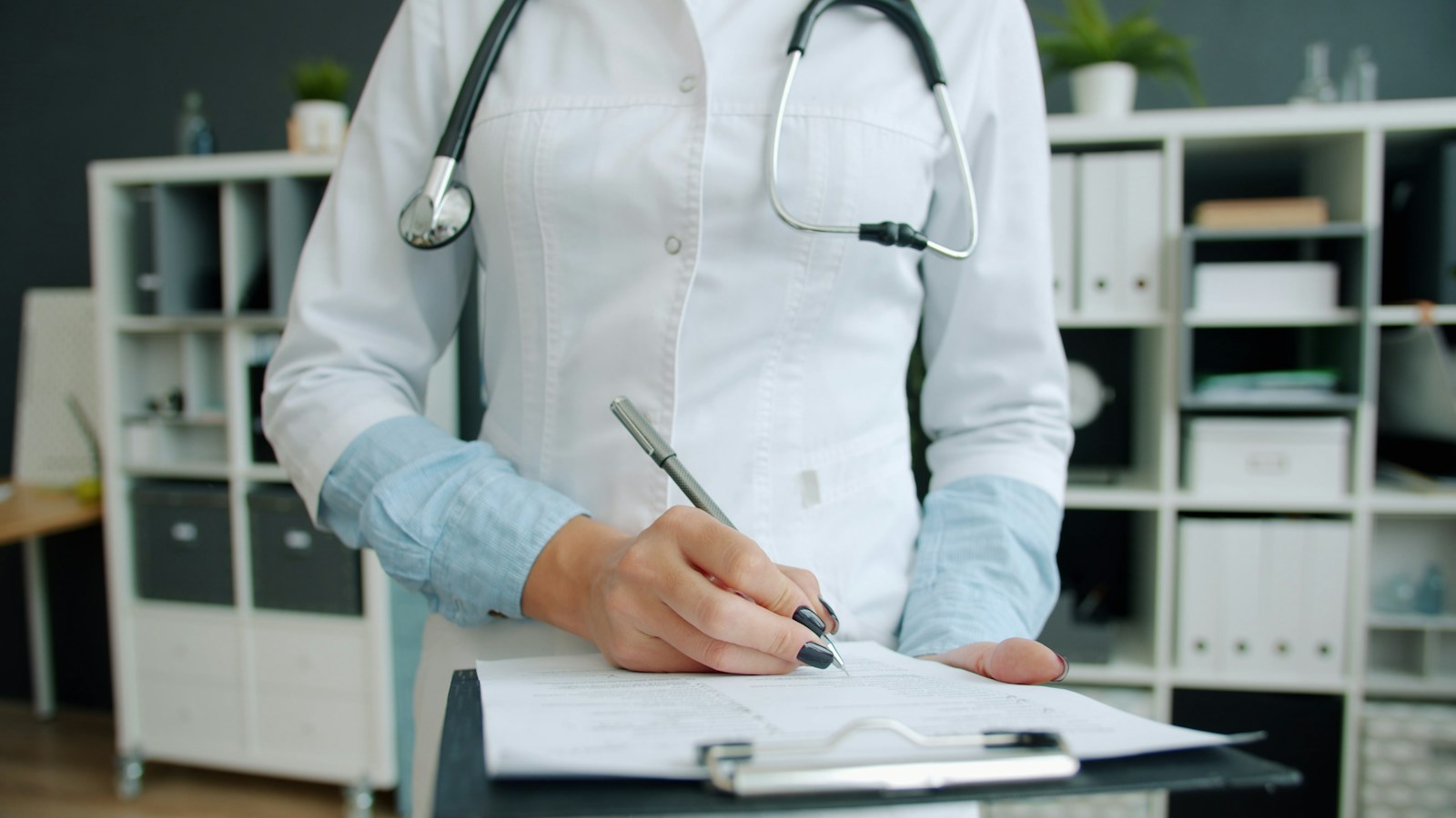 Doctor writing medical documentation on a clipboard